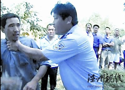 一村民欲阻止拆遷,被一個身穿監察大隊制服的工作人員掐住脖子,野蠻推開