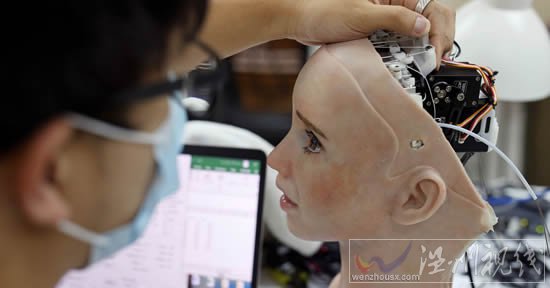 一名工程師調(diào)整人形機(jī)器人 Grace 的頭部